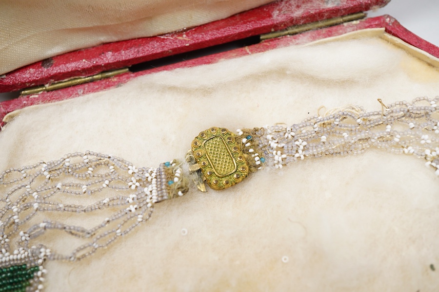 A glass bead necklace, early 19th century, intricately composed of woven glass beads depicting panels of butterflies and flowers, together with early 20th century correspondence from the Victorian & Albert Museum discuss